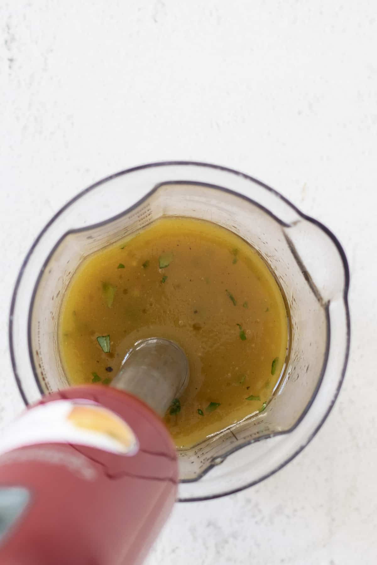 Using a hand blender to blend white balsamic dressing.