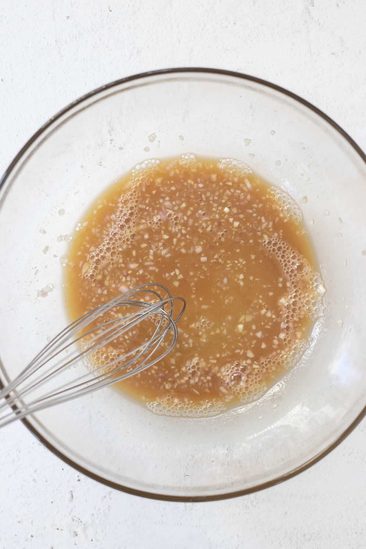 Whisking all of the dressing ingredients except for olive oil in a large bowl.