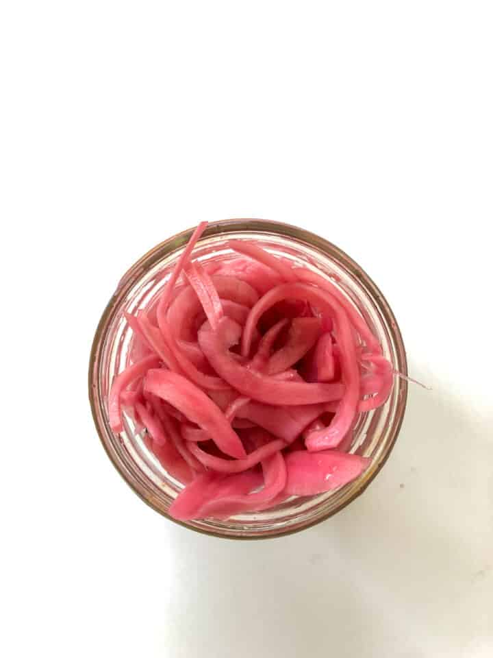 Overhead photo of pickled red onions in a small mason jar.