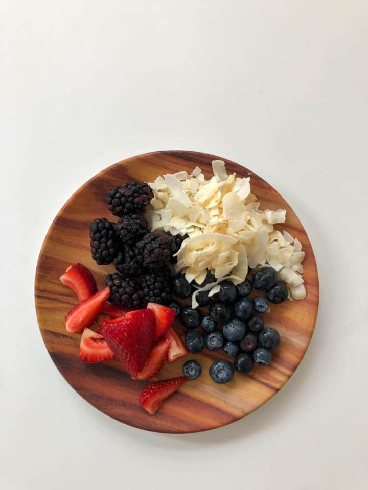 berries, and toasted coconut on a wooden plate