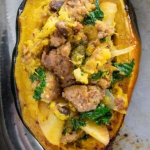 sausage and apple stuffed acorn squash on parchment paper