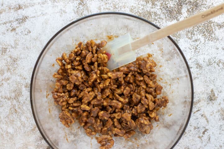 mixing walnuts in a large bowl with a rubber spatula