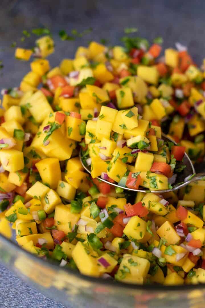close up photo of mango salsa on serving spoon.