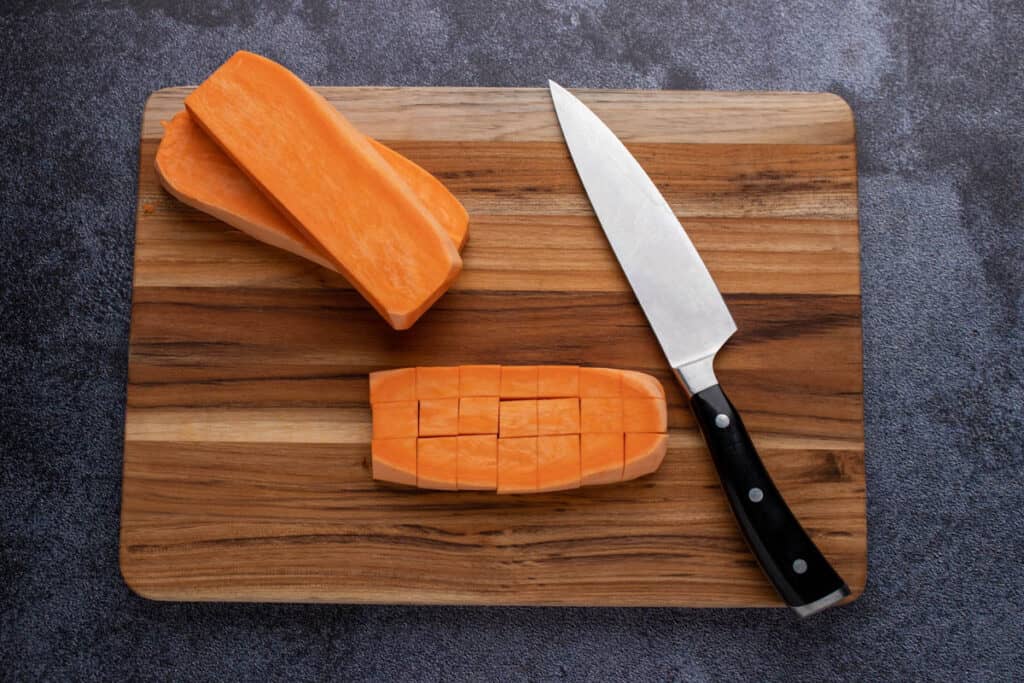 Cutting sweet potatoes into ½ inch cubes.
