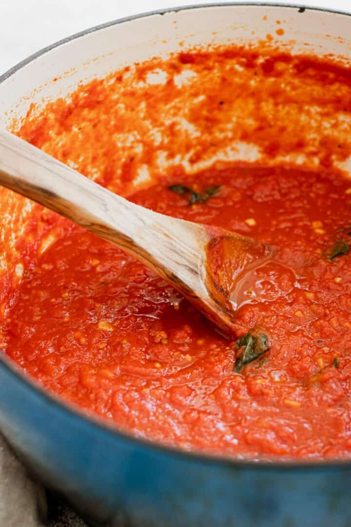Marinara sauce in a large pot with a wooden spoon.