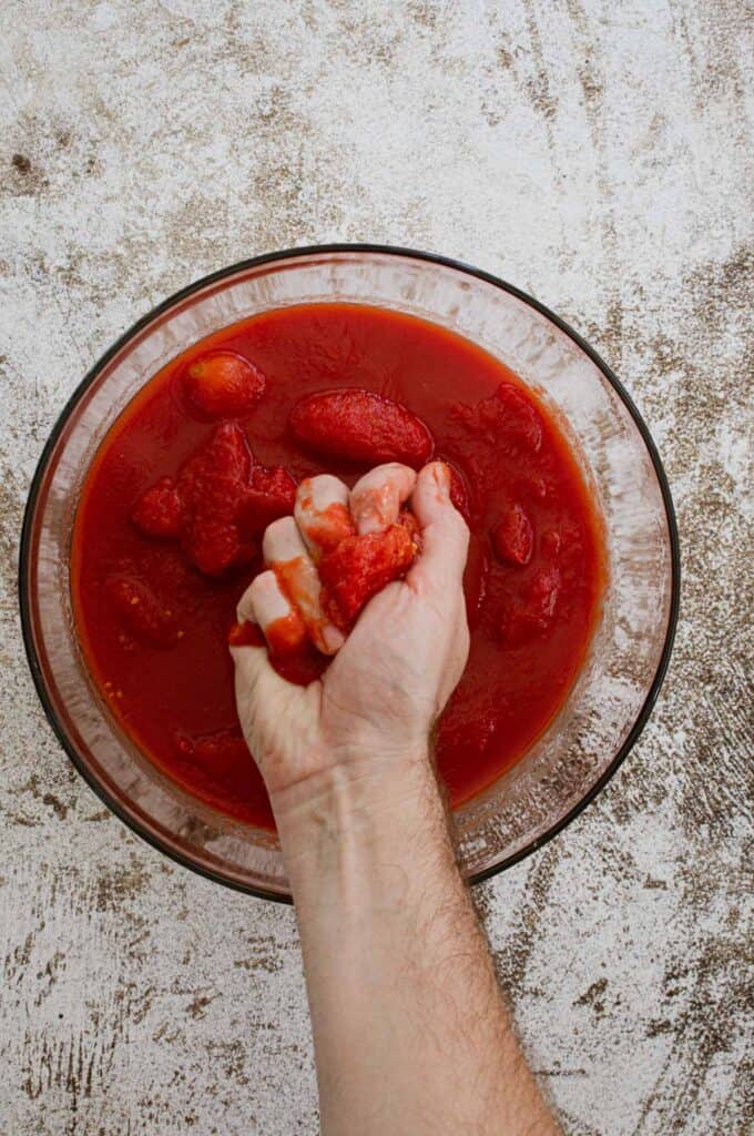 Crushing whole tomatoes.