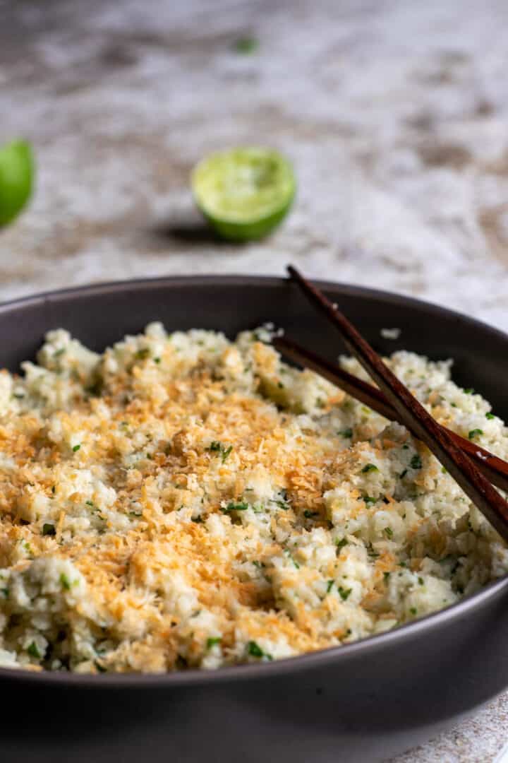 Close up view of toasted coconut cauliflower rice with chopsticks.