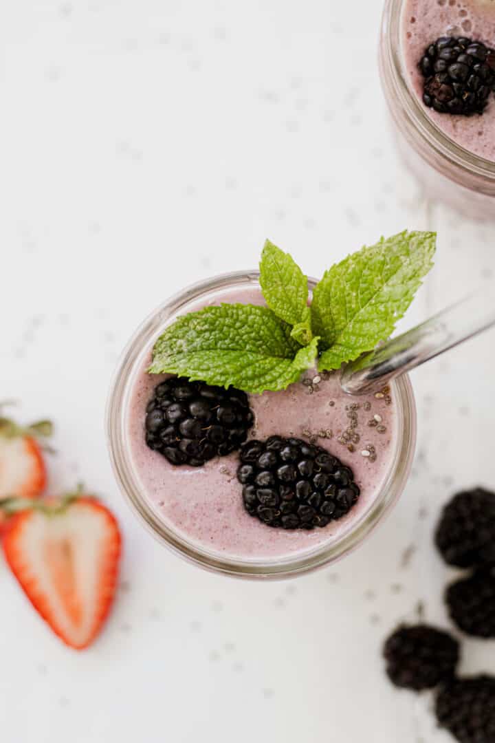 Smoothie in a glass mason jar with blackberries and mint.