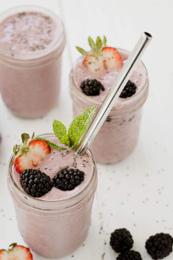 Three mason jars filled with a berry smoothie.