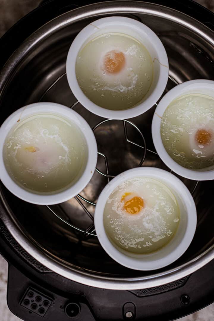 Air fryer poached eggs inside white ramekins.