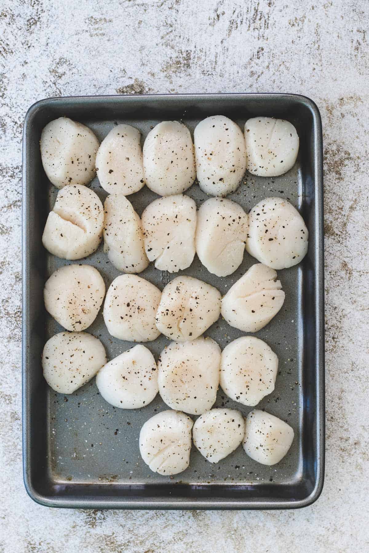Seasoned scallops on a small baking tray. 