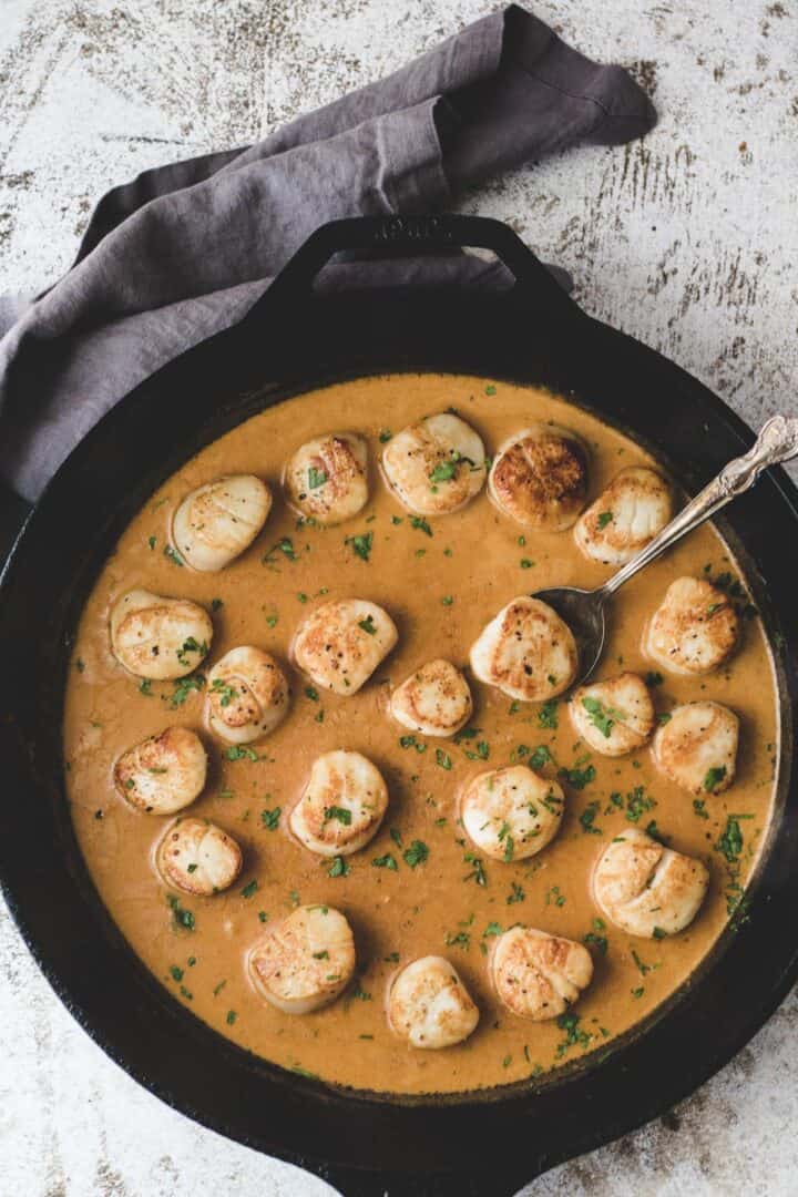 Sous vide scallops in cajun sauce with a spoon.