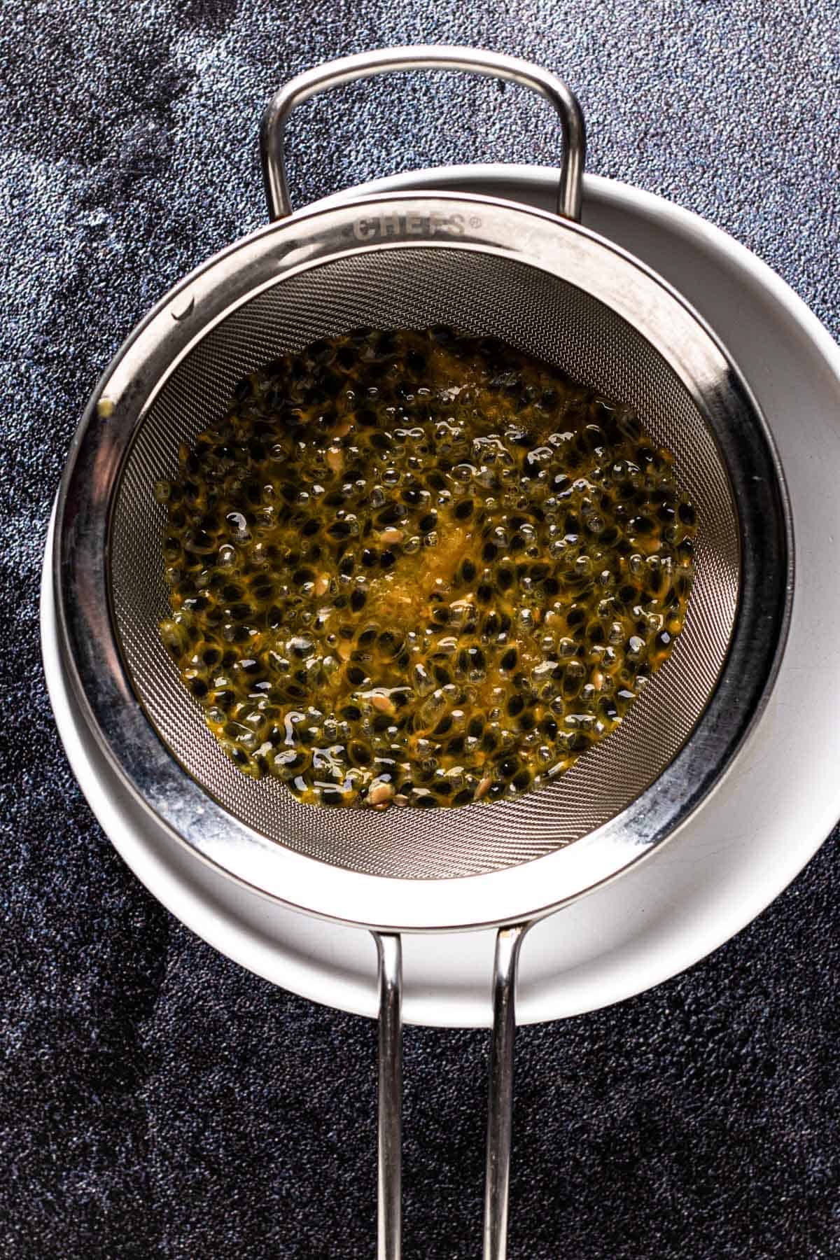 Straining passion fruit through sieve.