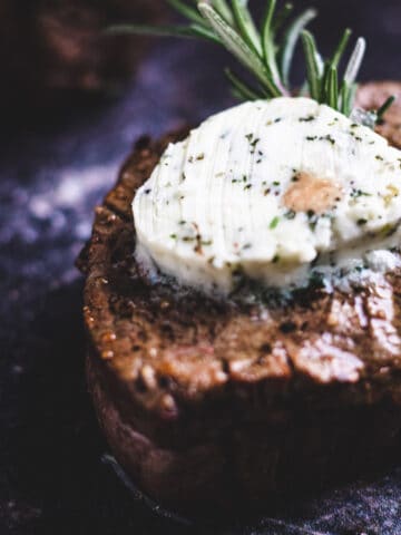 Air fryer filet mignon topped with garlic-herb butter and a sprig of rosemary.