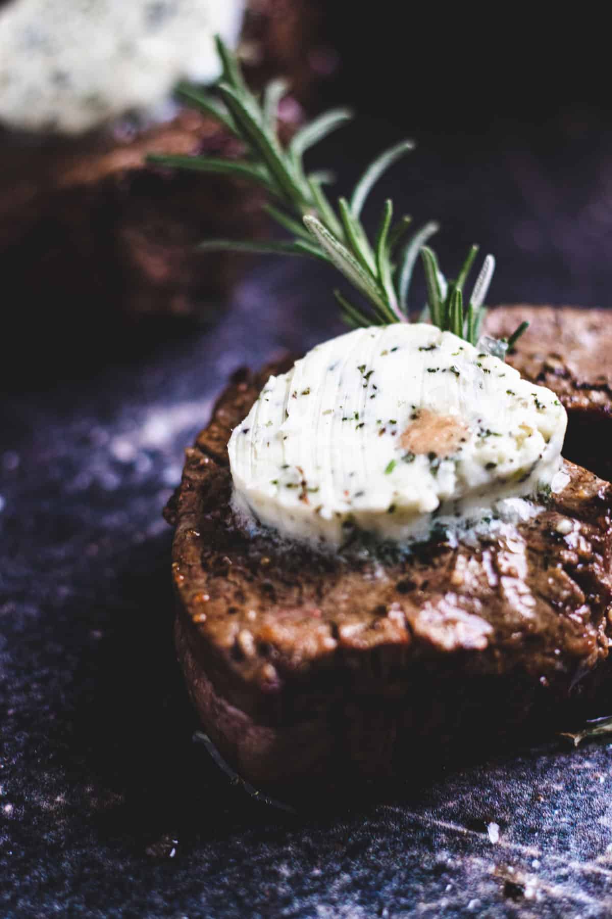 Close-up shot of air-fried filet mignon with compound butter and rosemary.
