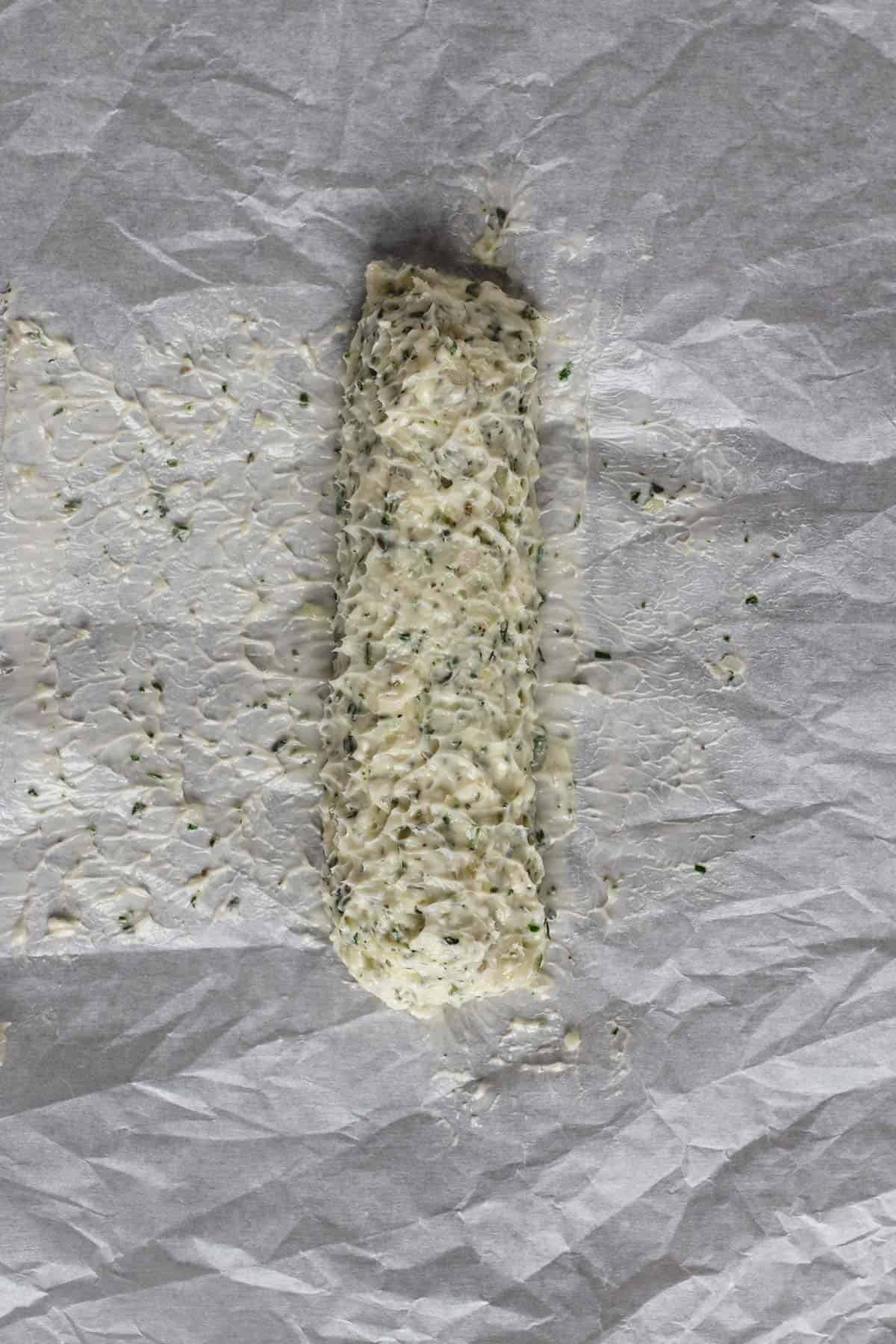 Rolling compound butter into a log with parchment paper.