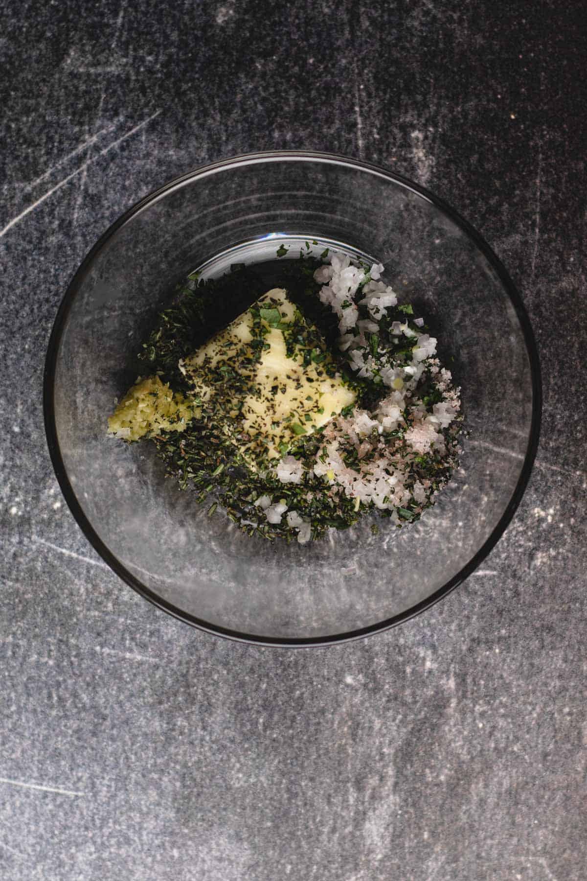 Garlic-herb ingredients in a small glass bowl.