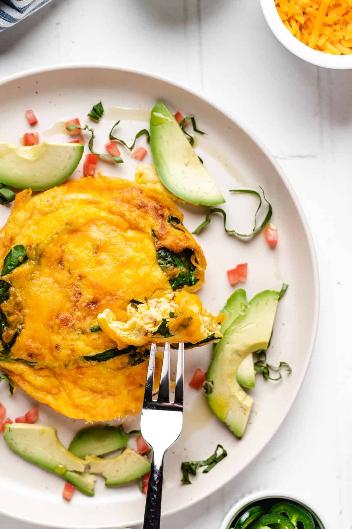 Air fryer omelette on a round white plate with a fork.