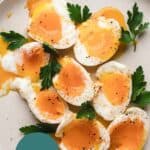 Runny eggs on a large plate with parsley.