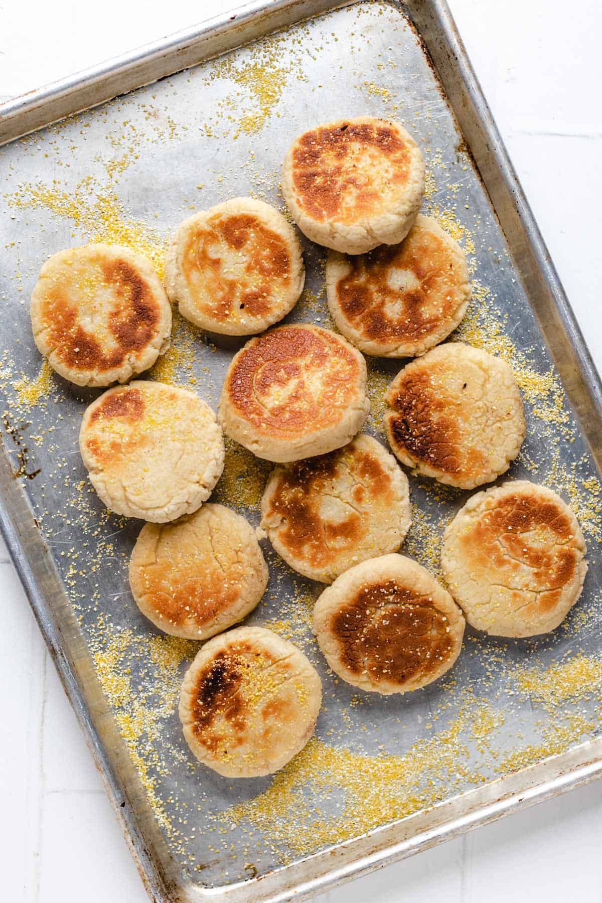 Overhead shot of cooked English muffins on a baking tray.