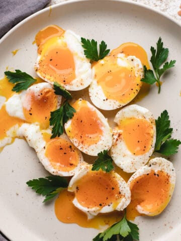 Soft boiled eggs on a large plate with parsley.