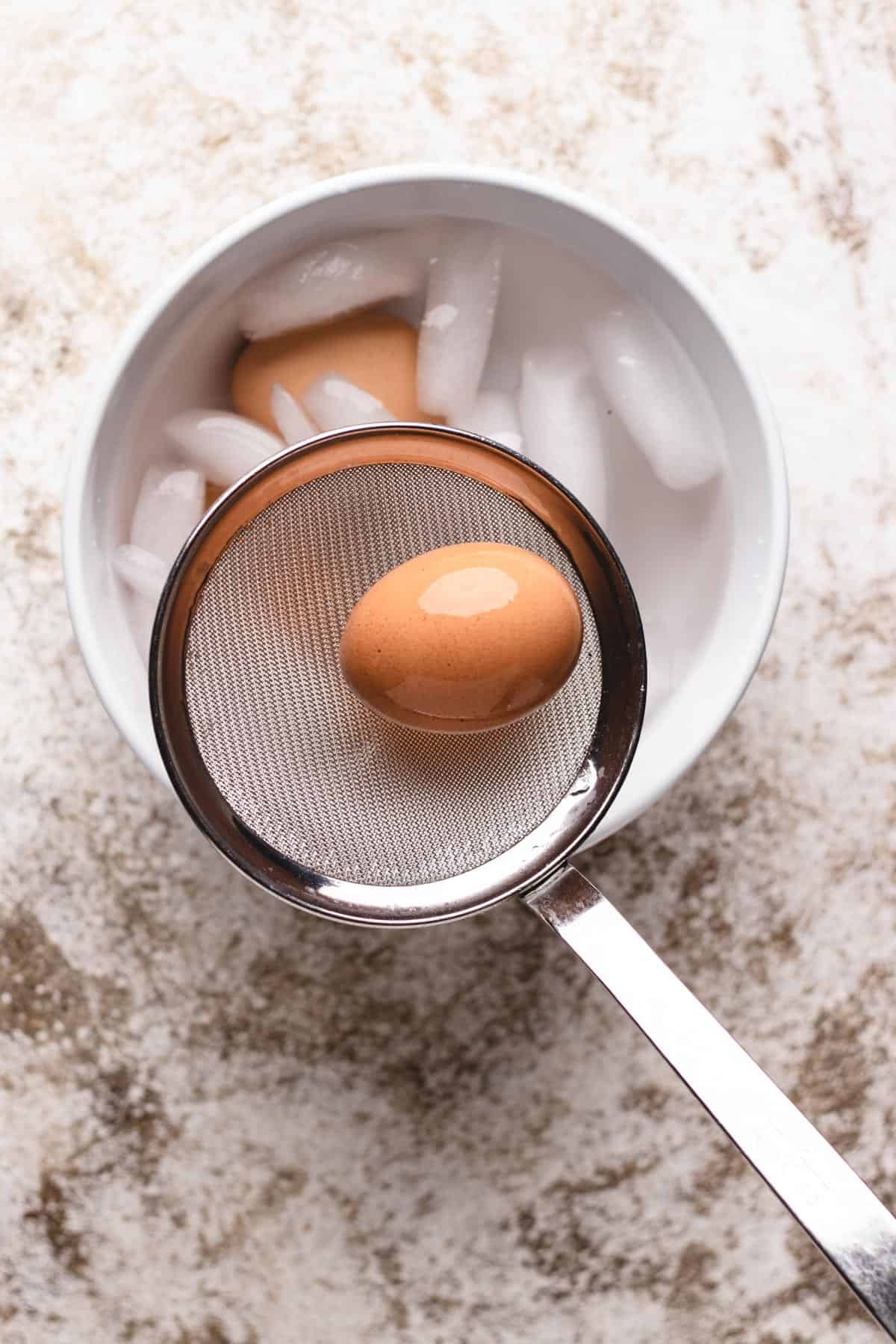 Removing soft boiled egg out of ice bath.