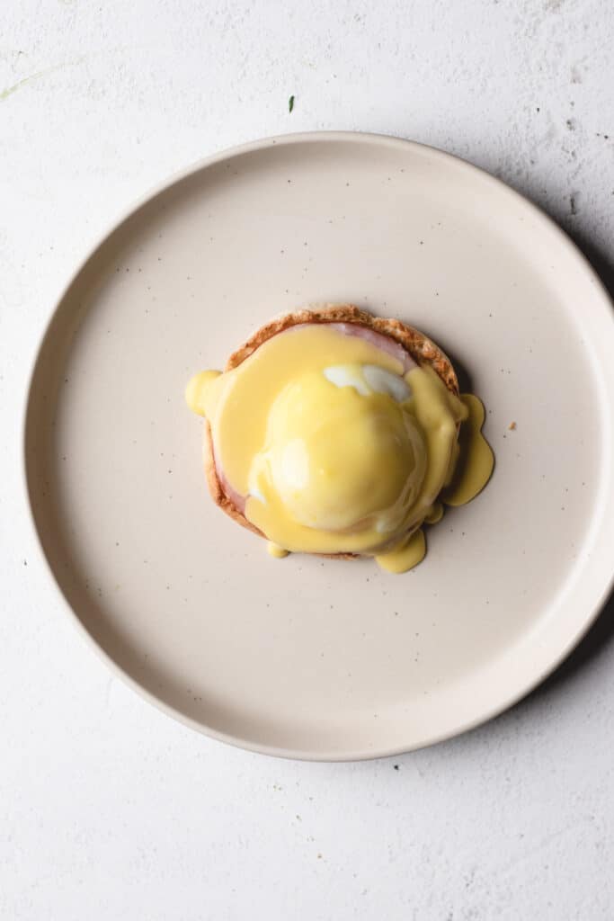 Covering eggs Benedict with a yellow hollandaise sauce.