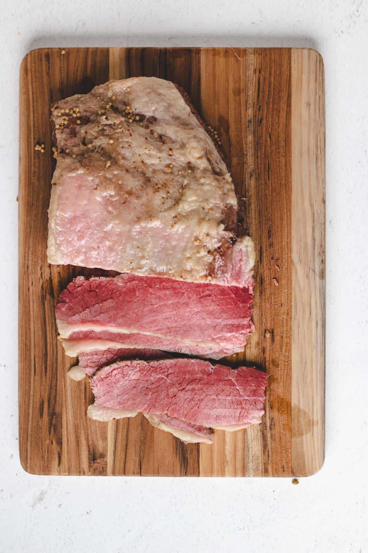A photo of sliced corned beef arranged on a wooden cutting board.