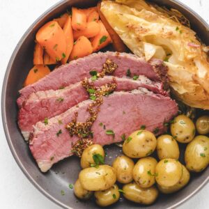 Close-up photo of a dinner plate filled with corned beef, cabbage, potatoes, and carrots.