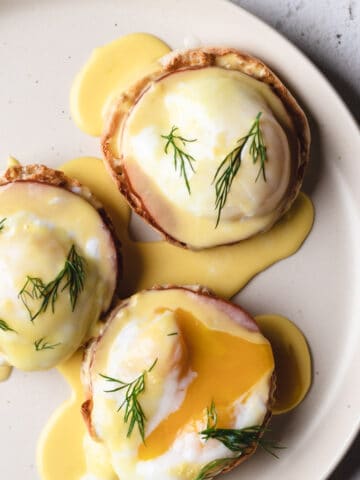 Image of a large plate with eggs benedict topped with hollandaise sauce.