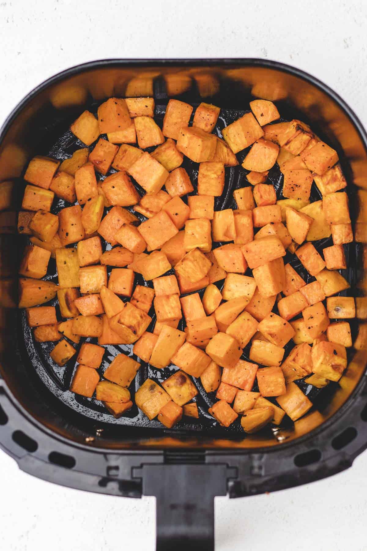 Diced sweet potatoes in an air fryer basket