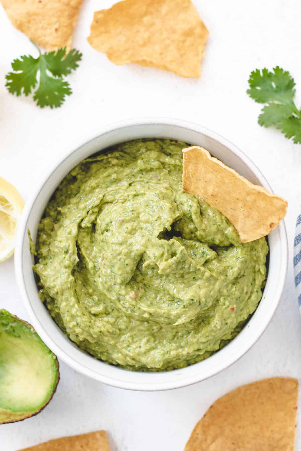 Overhead photo of guacamole in a bowl with a single tortilla chip.