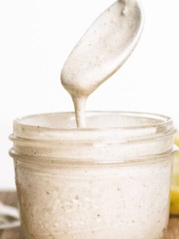A photo of a small mason jar filled with pepita crema with a spoon.