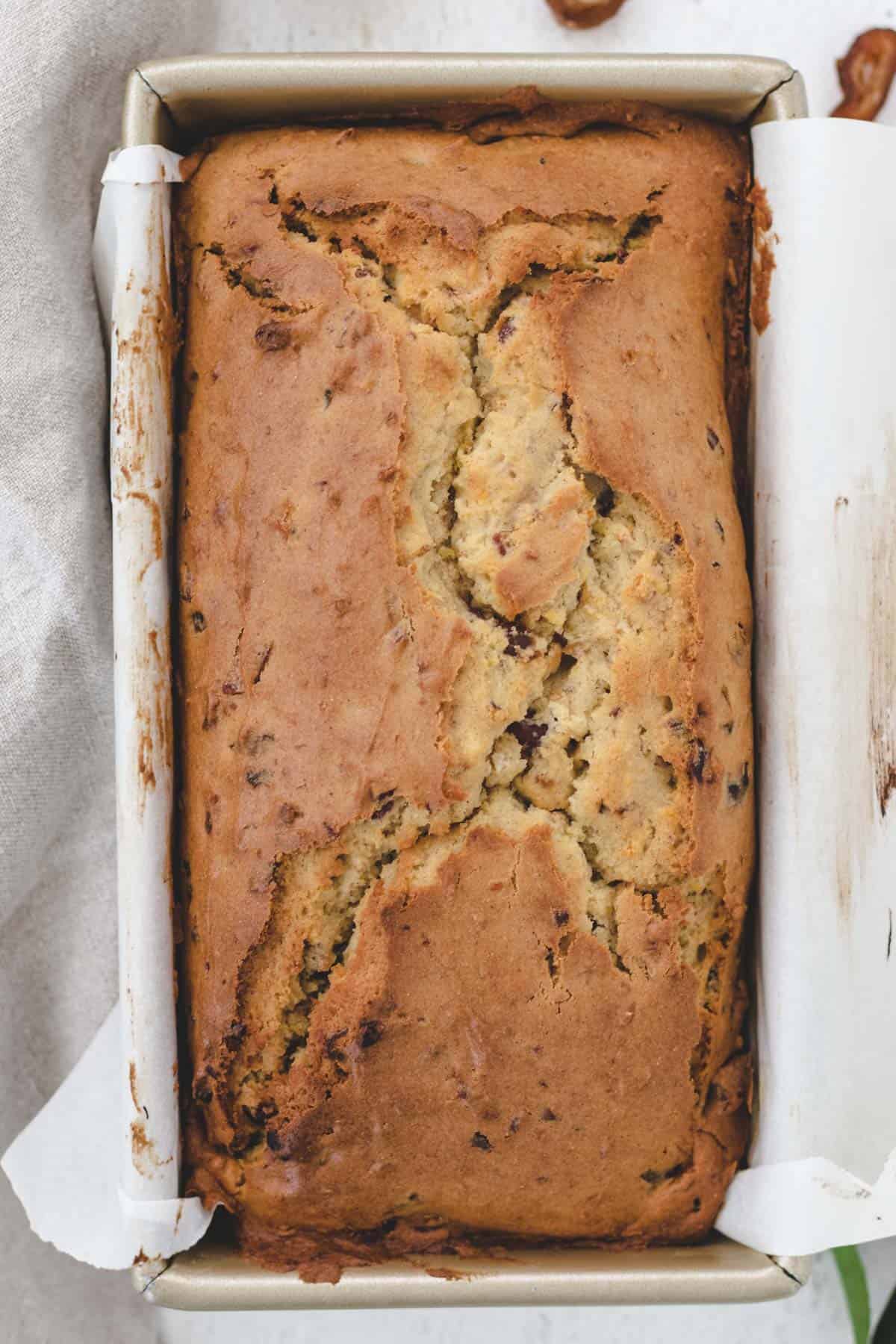 Baked bread loaf inside of a rectangular loaf pan.