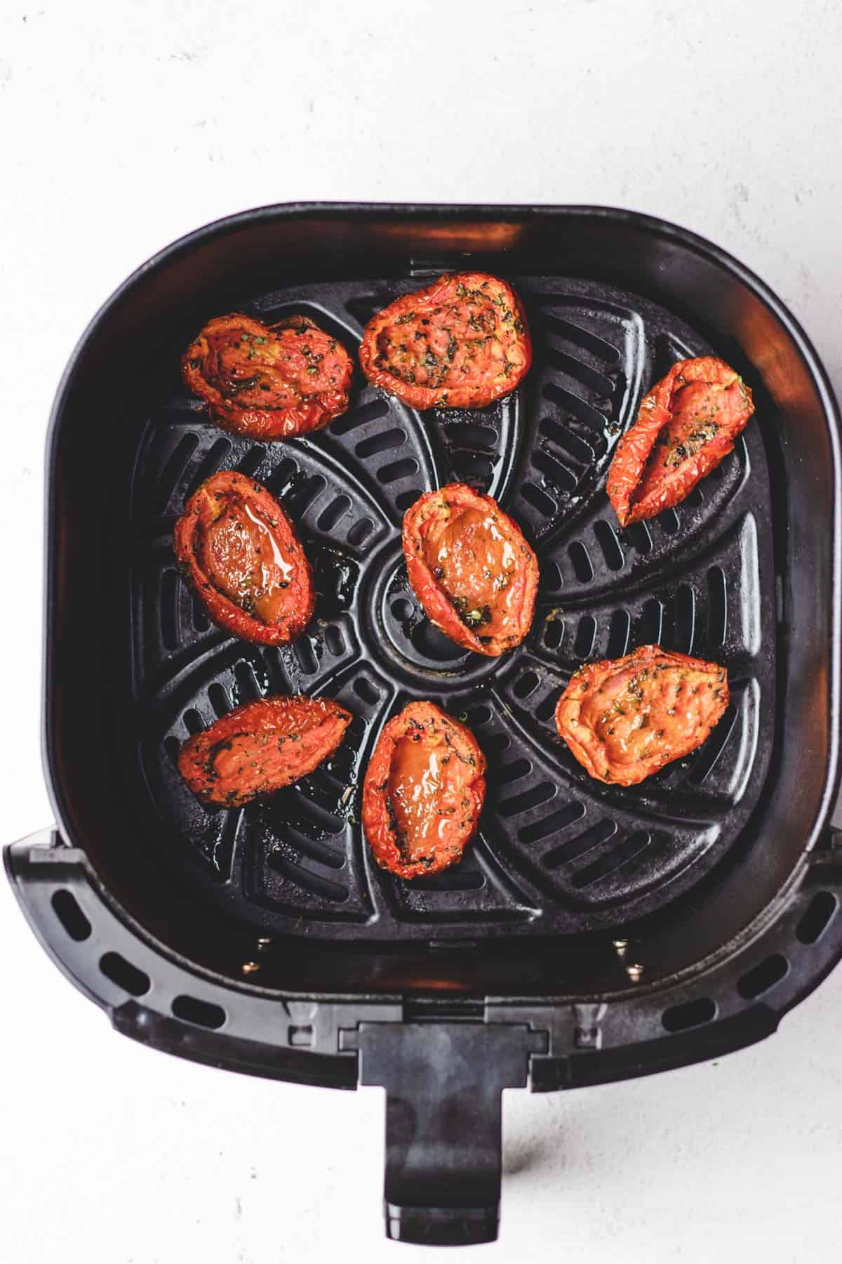 A photo of cooked slow roasted tomatoes in an air fryer basket.