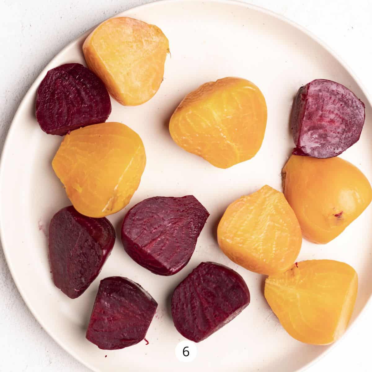 Cooked red and yellow beets on a large round plate.