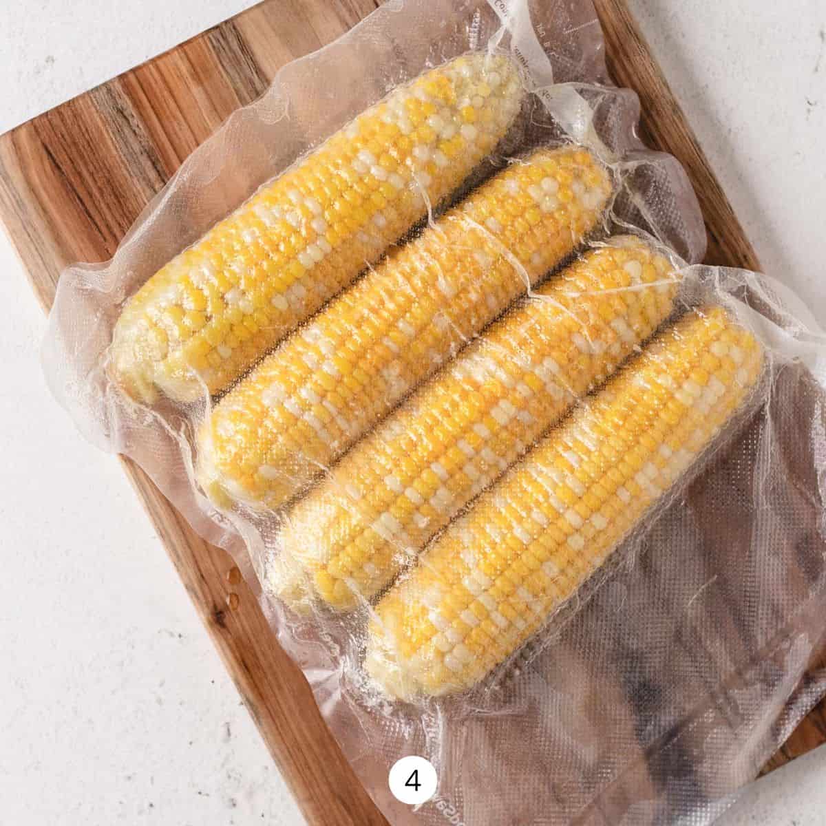 Sous vide bag of corn on top of a wooden cutting board.