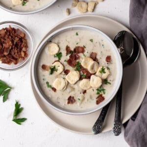 Clam chowder with oyster crackers, bacon bits, and parsley