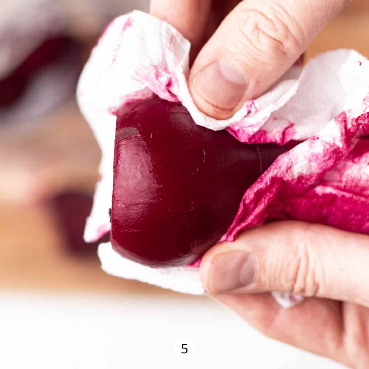 Peeling a red beet with a paper towel.