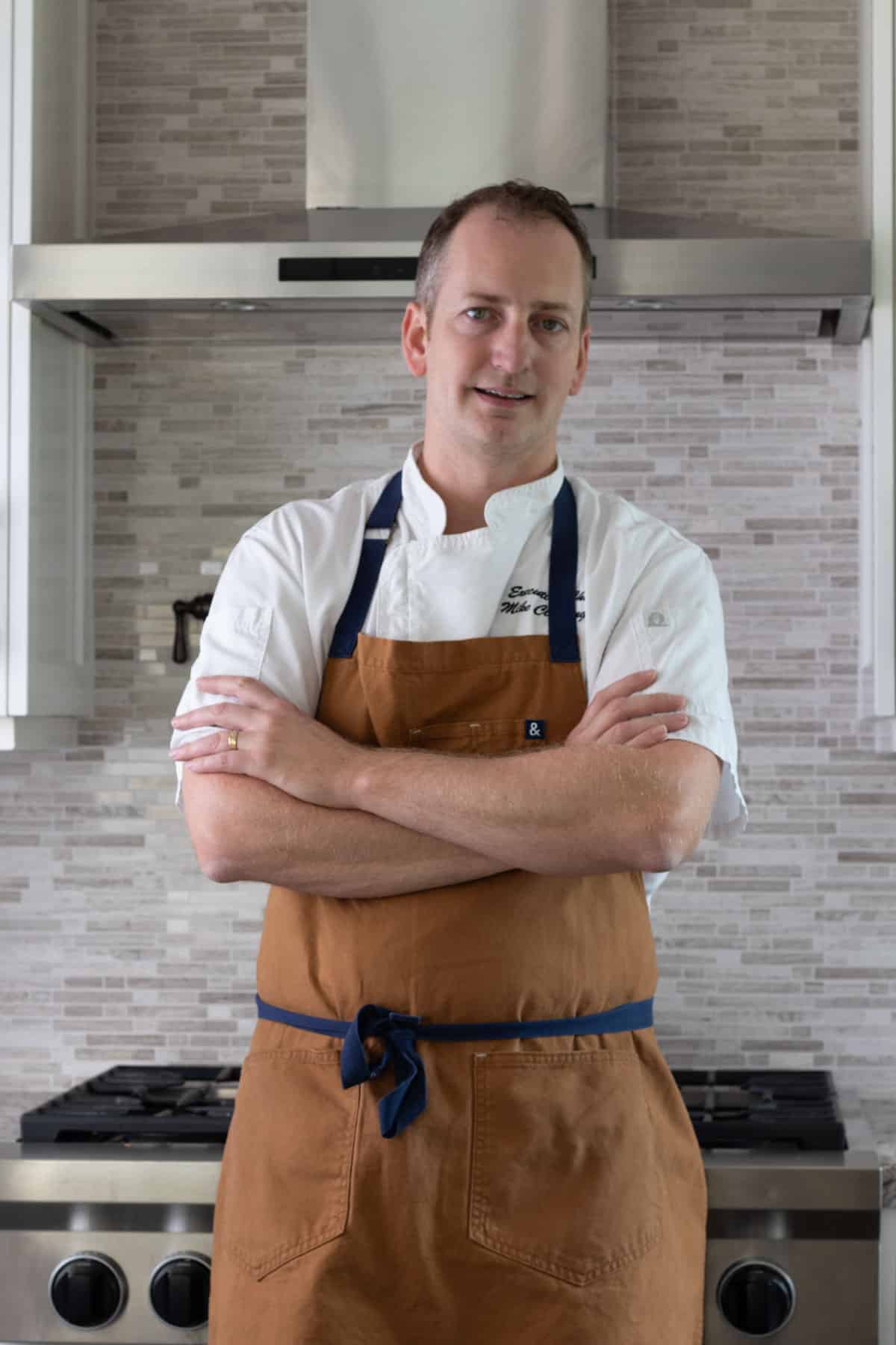 Standing in the kitchen with arms crossed in front of stove.