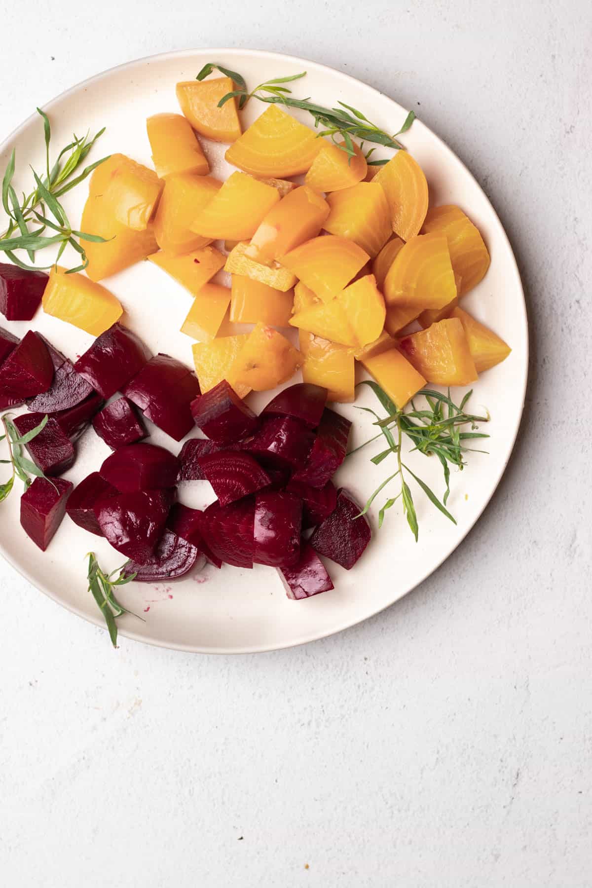 Large diced yellow and red beets on a large round plate.