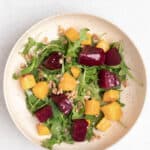 Beets on top of an arugula salad with butternut squash, and faro.