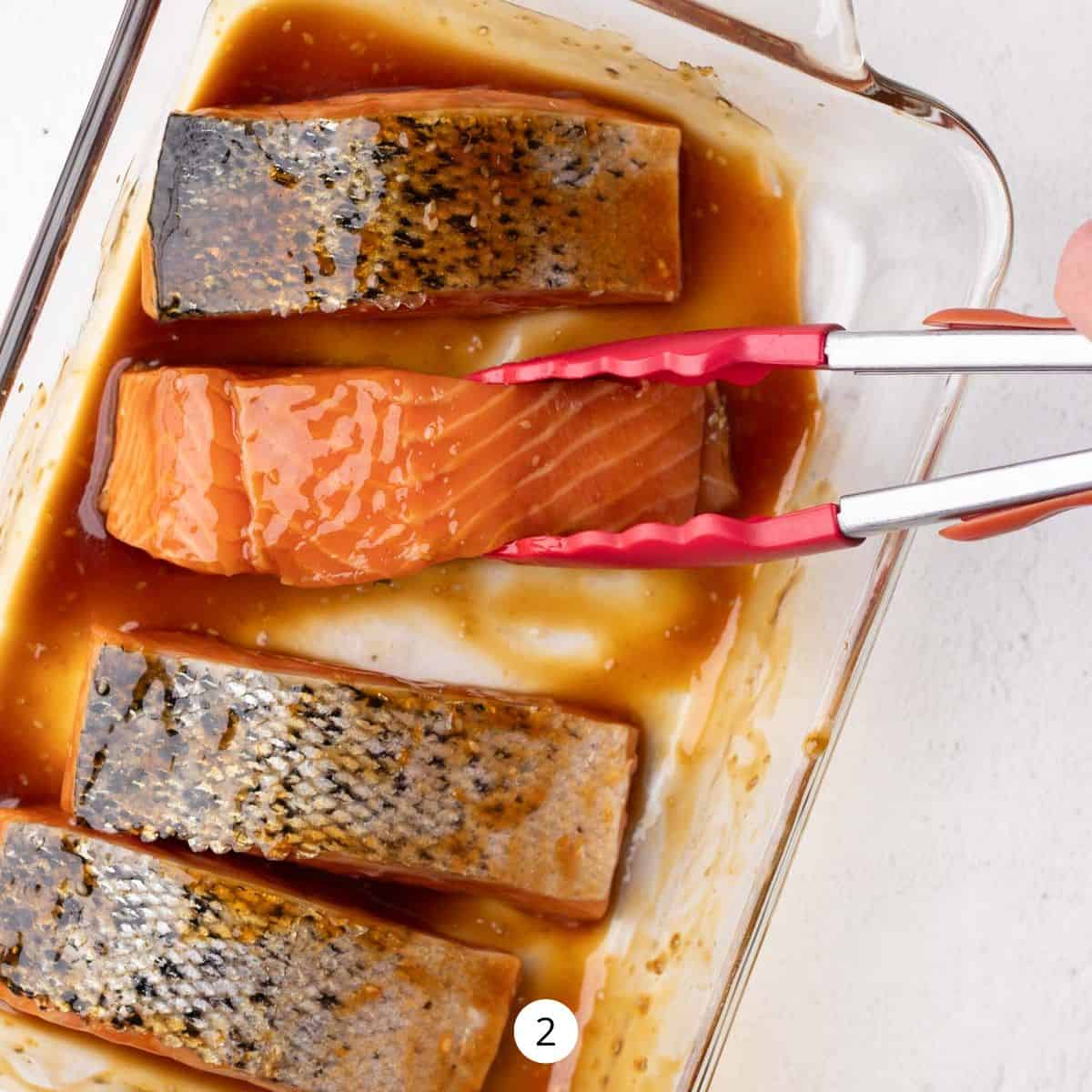 Marinating salmon in a glass casserole dish with teriyaki sauce.
