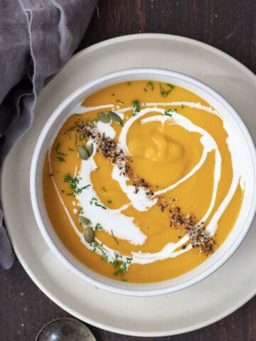 Butternut squash soup garnished with coconut milk, pumpkin seeds, chives, and fresh cracked pepper.