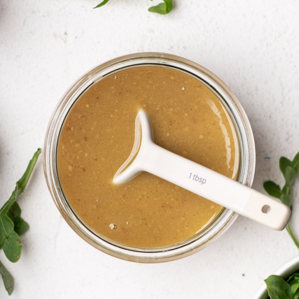 Maple Dijon dressing inside of a round glass mason jar.