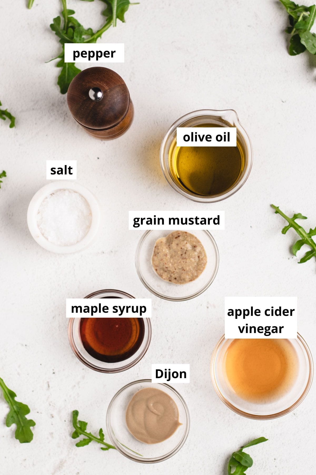 Dijon mustard, grain mustard, salt, pepper, maple syrup, apple cider vinegar, and olive oil in small round bowls.