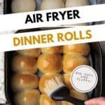 Brushing cooked dinner rolls with melted butter inside of an air fryer basket.