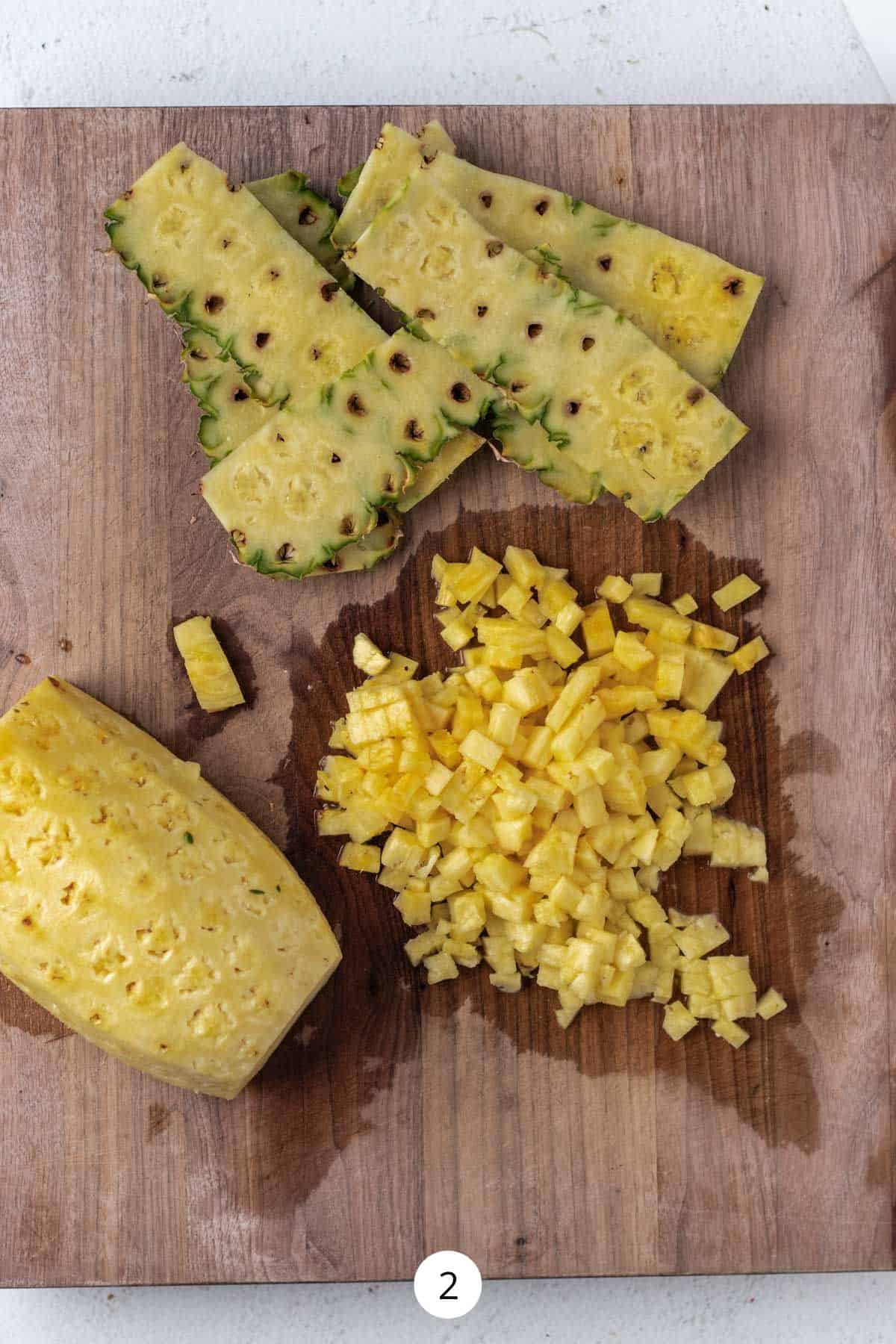 Peeled and chopped pineapple on a large wooden cutting board.