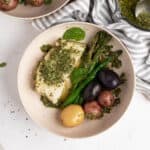 Halibut with a Chimichurri sauce, asparagus, and baby potatoes, presented inside of a round bowl.