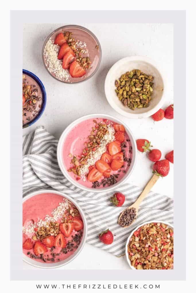 Four bowls filled with strawberry smoothie and toppings.